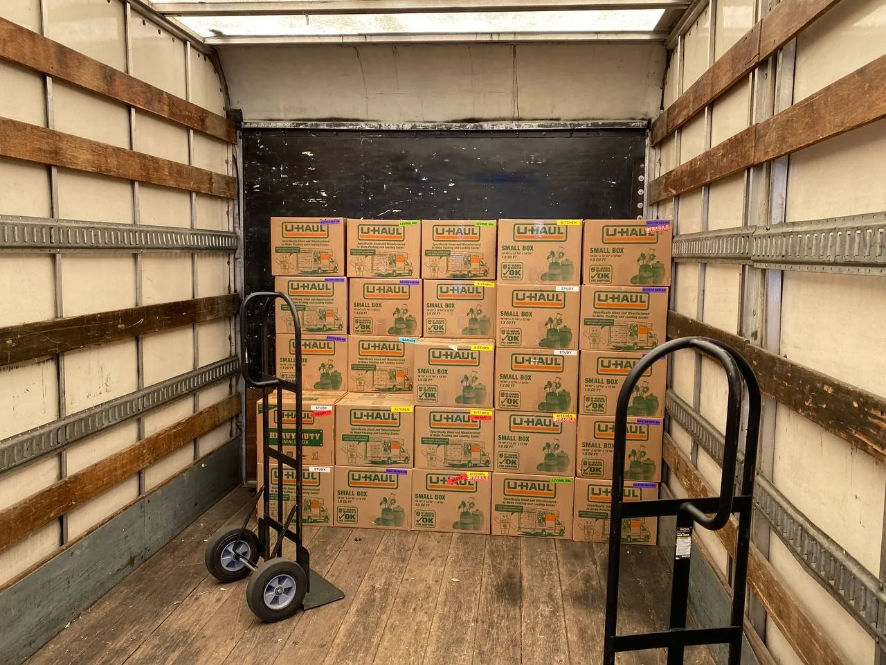 Uniform boxes stacked wall to wall in a truck with two hand trucks in front