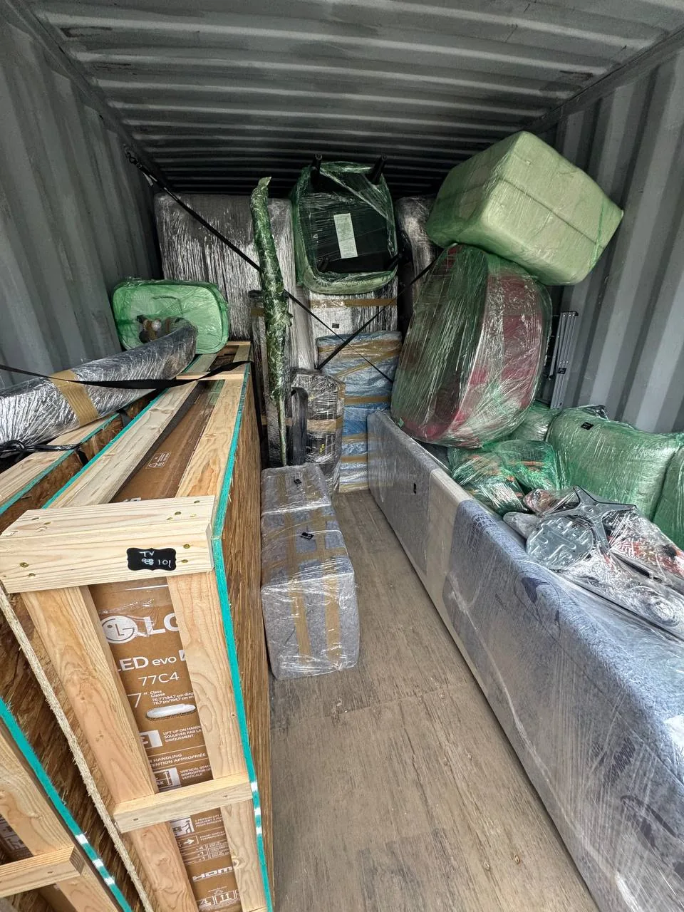 A storage container loaded front to back with wrapped furniture and a crated TV