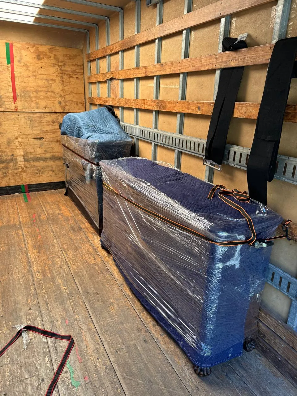 A dresser wrapped in blankets and strapped to the wall of a truck