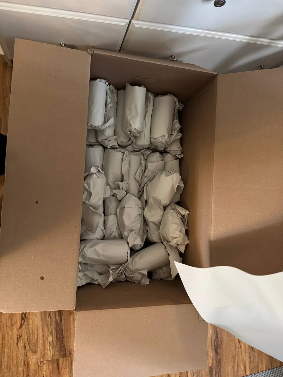 A box filled with glasses, each one wrapped in packing paper