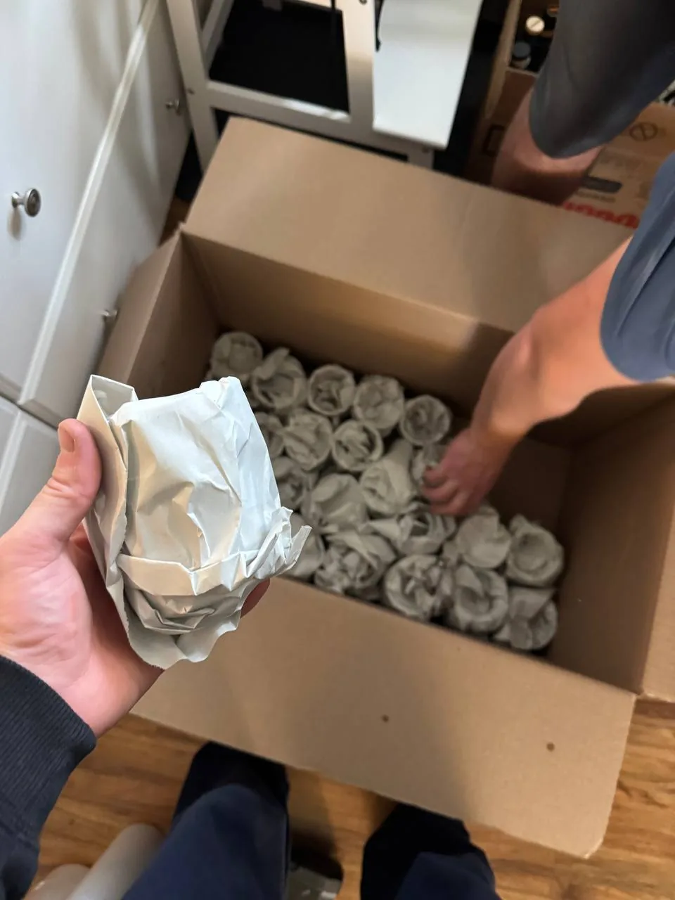A mover wrapping glasses in packing paper and setting them into a box