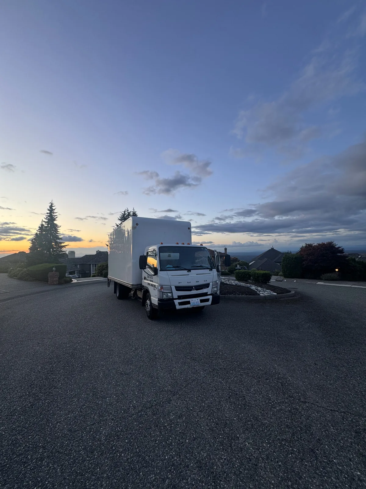 A moving truck parked on a hilltop street at dusk