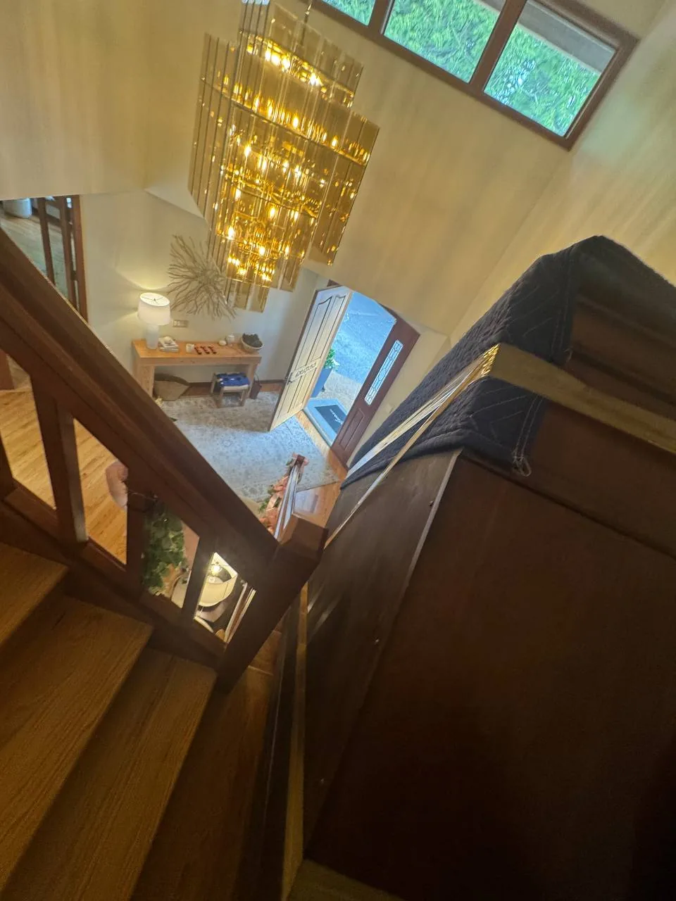 Padded dresser being carried down a staircase under a chandelier