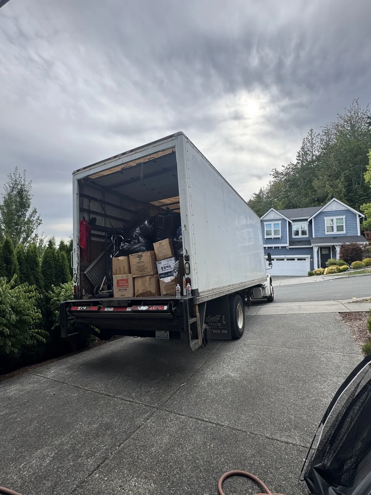 A truck backed up to a house with boxes loaded at the door