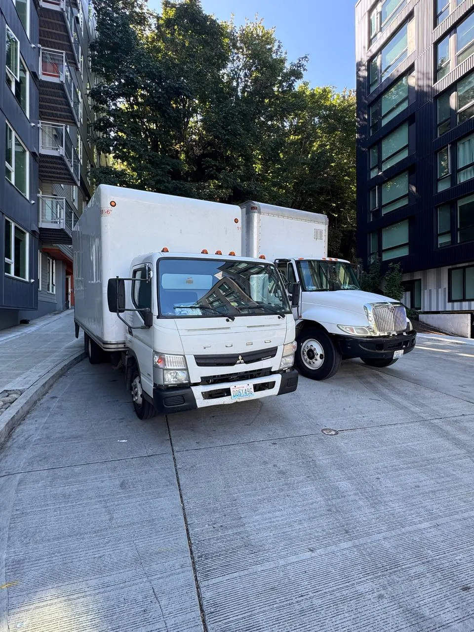 Two Strok box trucks parked in front of a mid rise building